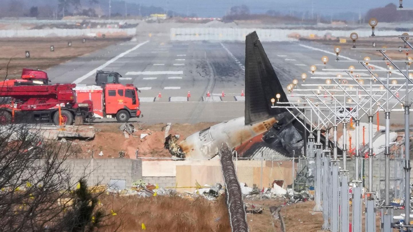 Hinter einer Mauer liegt ein Flugzeugwrack auf dem Flughafen in Muan, Südkorea