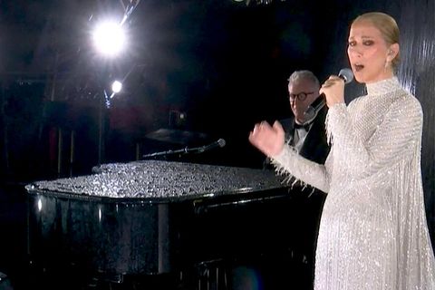 Sängerin Céline Dion in einem langen weißen Kleid, neben ihr ein Pianist an einem Konzertflügel
