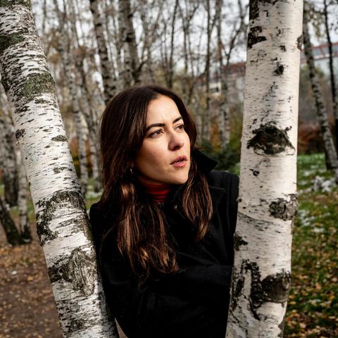 Aline Abboud,  deutsche Journalistin, lehnt an einer Birke