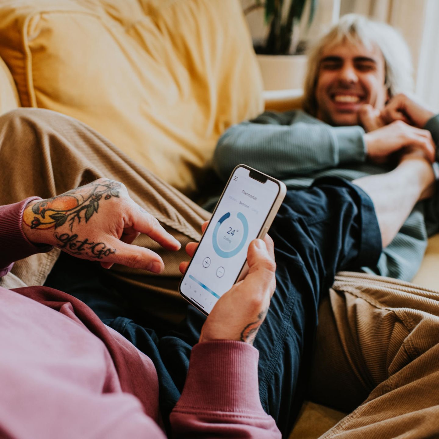 Strom sparen: Ein Pärchen liegt auf der couch und checkt den Stromerbrauch per App