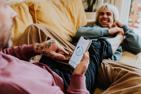 Strom sparen: Ein Pärchen liegt auf der couch und checkt den Stromerbrauch per App