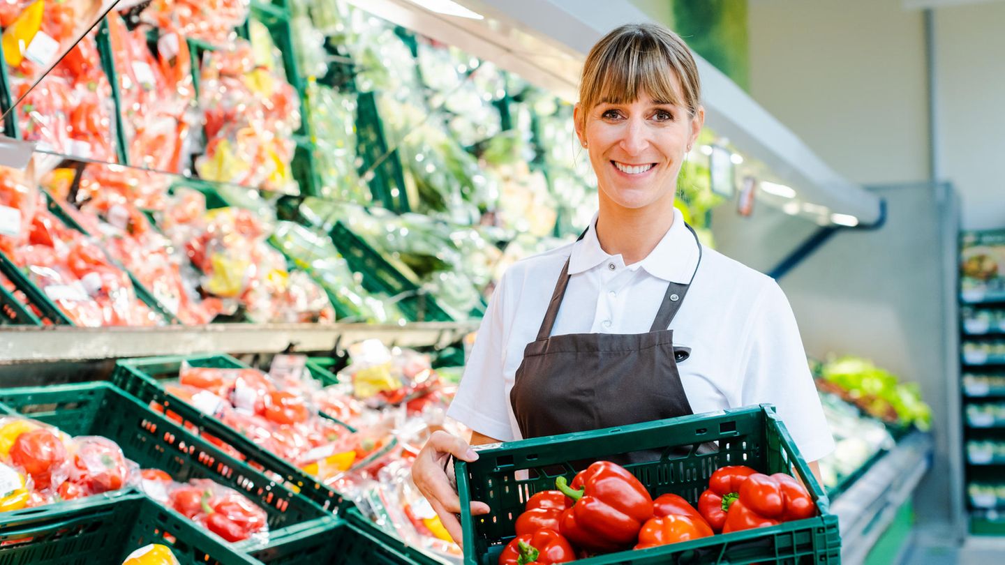Eine Angestellte in der Gemüseabteilung eines Supermarktes