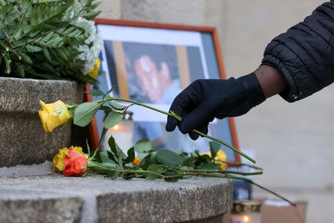 Jemand legt eine Rose vor ein Foto von Oury Jalloh