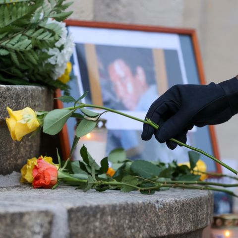 Jemand legt eine Rose vor ein Foto von Oury Jalloh