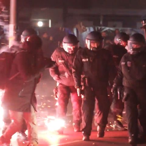 Einsatzkräfte der Polizei stehen in der Silvesternacht zwischen brennendem Feuerwerk in Berlin Neukölln