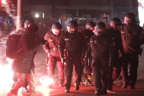 Einsatzkräfte der Polizei stehen in der Silvesternacht zwischen brennendem Feuerwerk in Berlin Neukölln