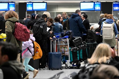 Reisende bilden am Düsseldorfer Flughafen beim Check-In eine Schlange