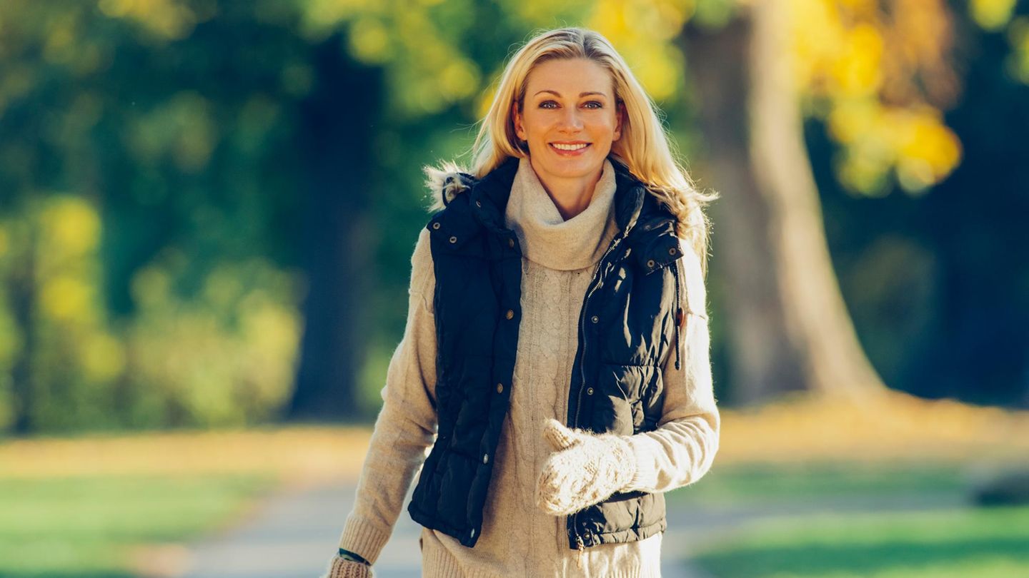 Portrait of smiling woman wearing warm clothes walking in a park