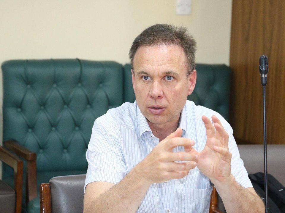 Carsten Wieland in weißem Hemd vor grünem Sofa