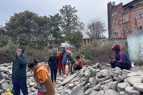 Menschen in Kathmandu versammeln sich vor ihren Häusern neben Trümmern nach einem Erdbeben