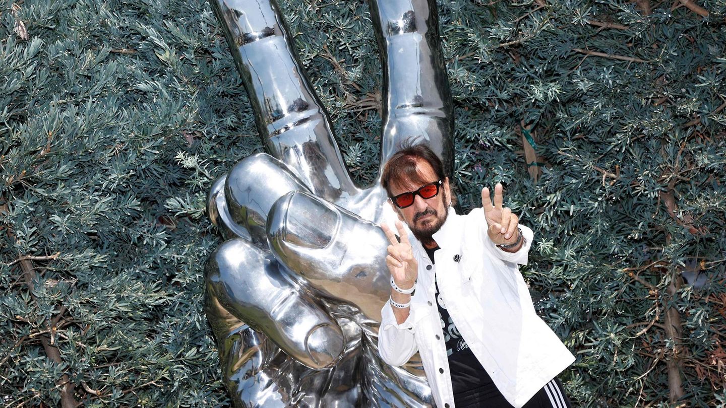 Ex-Beatle Ringo Starr posiert mit Peace-Zeichen vor einer Peace-Zeichen Statue Ex-Beatle Ringo Starr posiert mit Peace-Zeichen vor einer Peace-Zeichen Statue