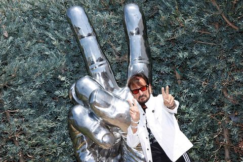 Ex-Beatle Ringo Starr posiert mit Peace-Zeichen vor einer Peace-Zeichen Statue