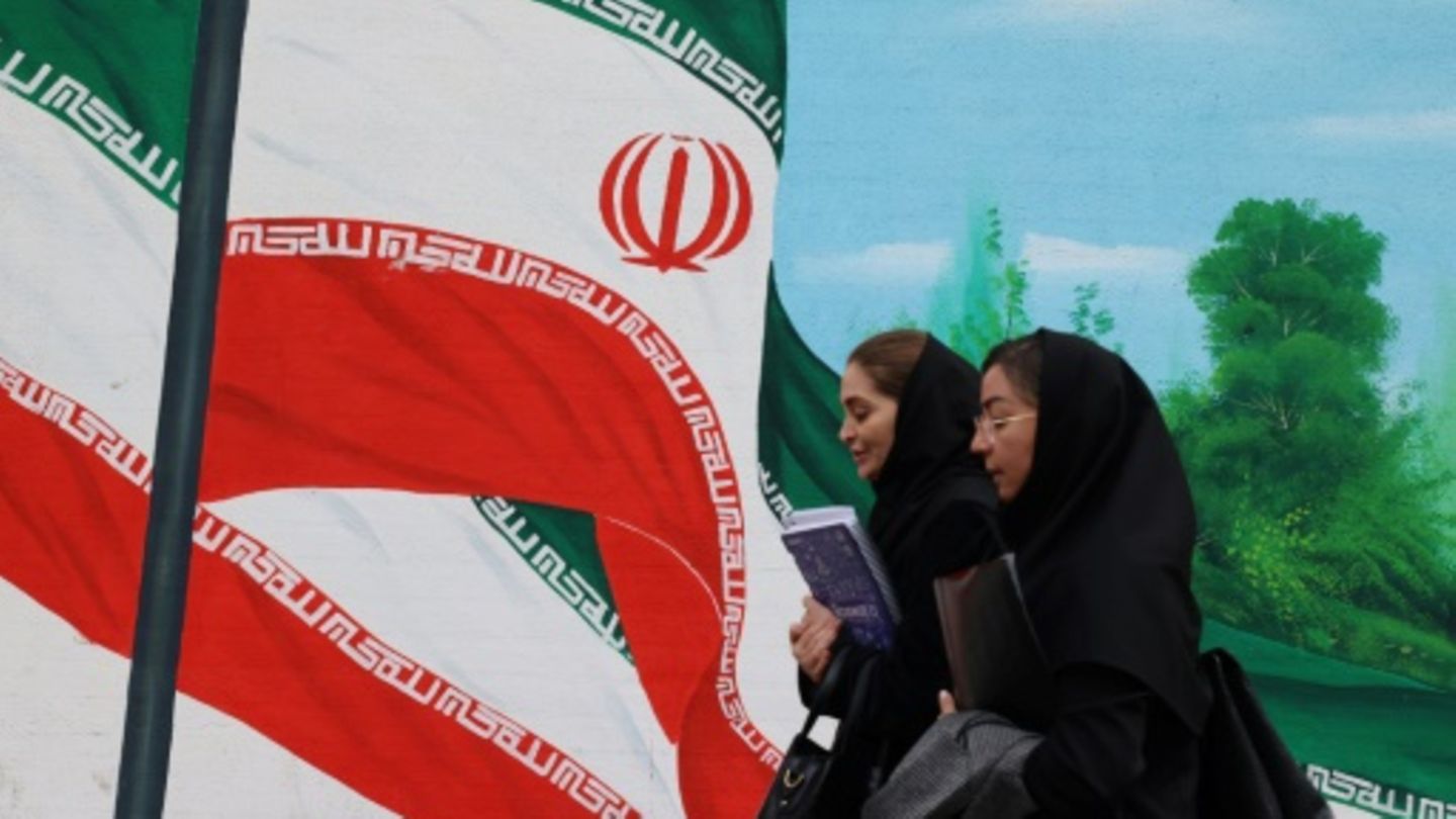 Frauen vor einem Bild der iranischen Flagge in Teheran