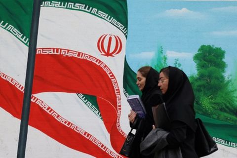 Frauen vor einem Bild der iranischen Flagge in Teheran