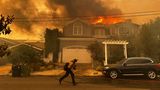 Ein Wohnhaus brennt, während ein Feuerwehrmann gegen das Palisades-Feuer im Stadtteil Pacific Palisades in Los Angeles kämpft
