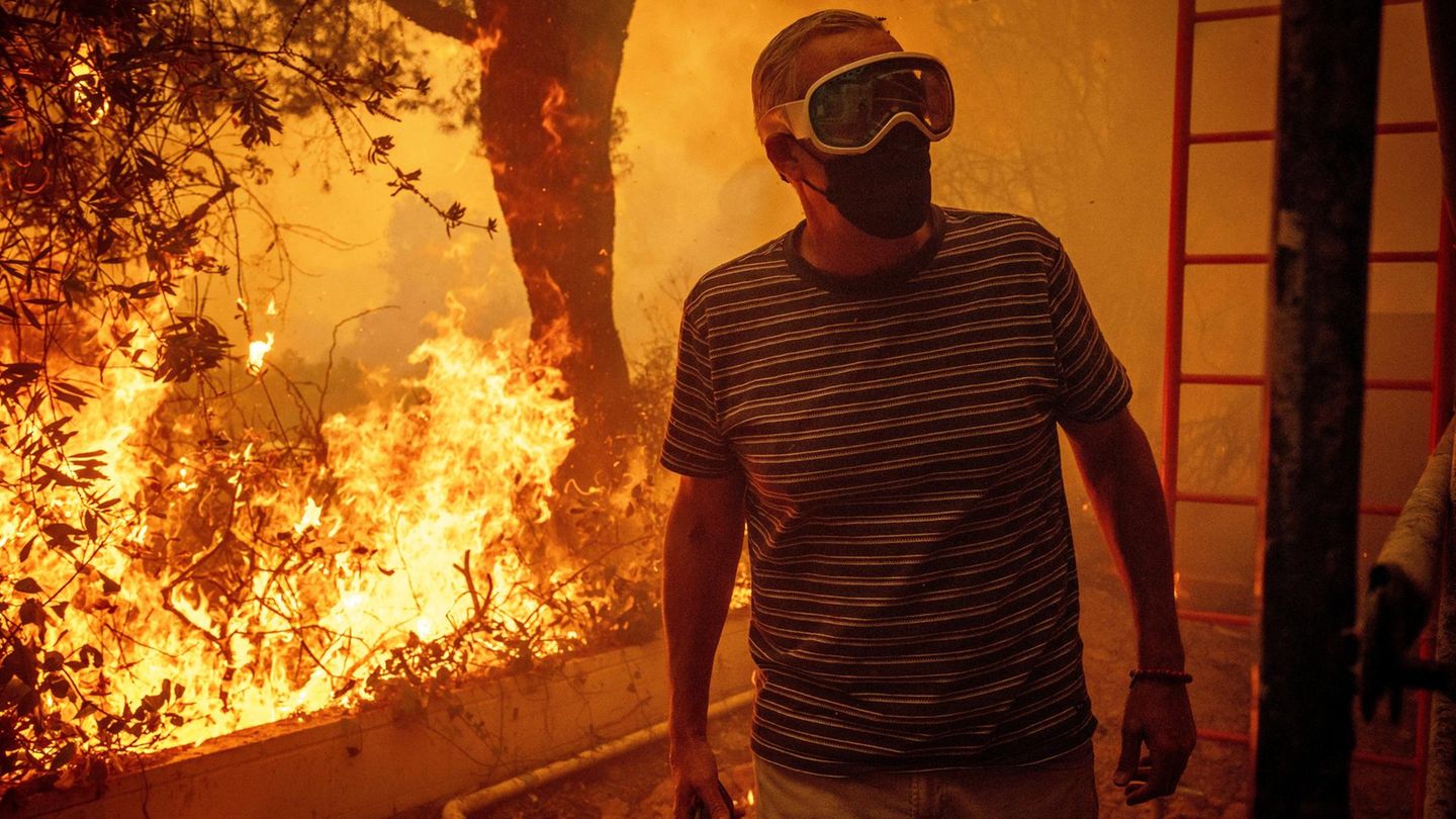 Mit Atemmaske und Schutzbrille steht ein Mann Dienstag auf seinem Grundstück in Pacific Palisades. Die Flammen sind bereits gefährlich nah