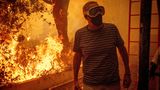 Mit Atemmaske und Schutzbrille steht ein Mann Dienstag auf seinem Grundstück in Pacific Palisades. Die Flammen sind bereits gefährlich nah