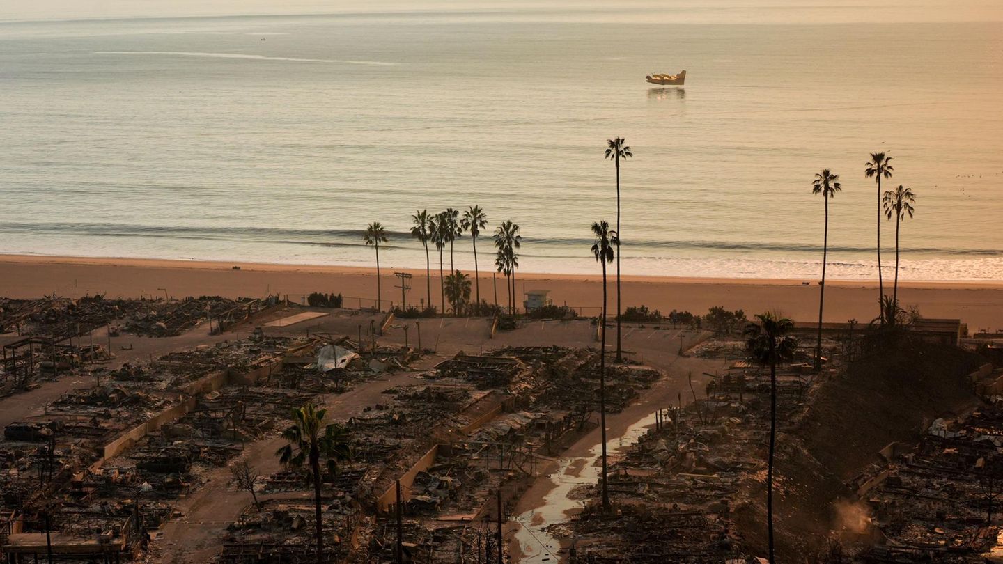Nichts als Zerstörung: Bis an den Pazifik sind die Häuser in Pacific Palisades, einem Stadtteil von Los Angeles, am Donnerstag niedergebrannt. Im Hintergrund füllt ein Löschflugzeug seine Wassertanks im Meer auf