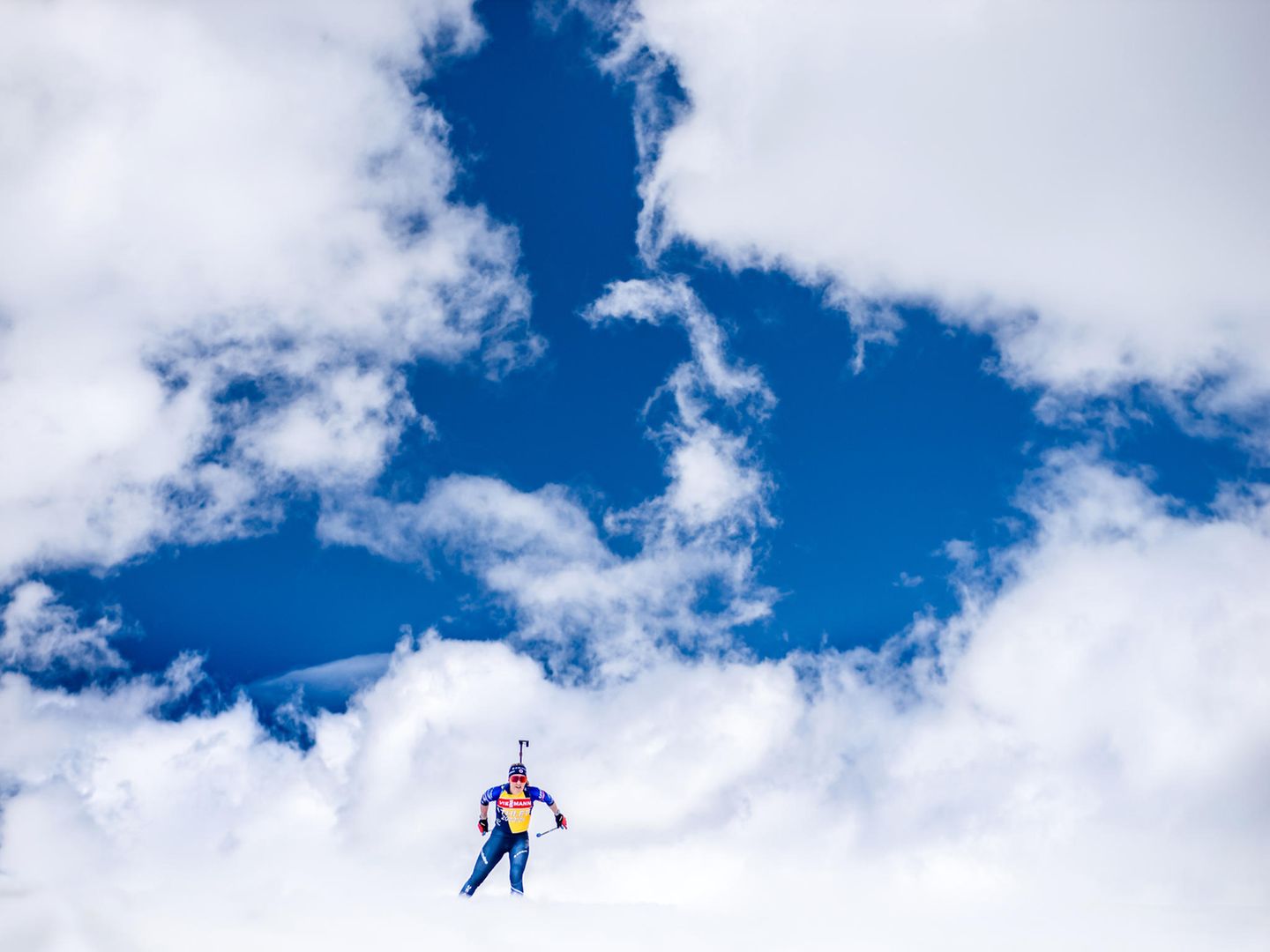 Sportfoto: Eine Biathletin vor einem blauen Wolkenhimmel