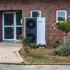 Eine Wärmepumpe steht vor einem Backsteinhaus