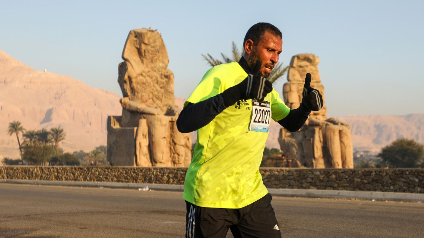 Luxor, Ägypten. Ein Läufer beim 32. Ägyptischen Marathon mit offenbar guter Laune. Die Marathonstrecke beginnt vor dem Hatschepsut-Tempel und führt an weitern antiken Stätten wie den Memnonkolossen, Medinet Habu und dem Tal der Könige und Königinnen entlang