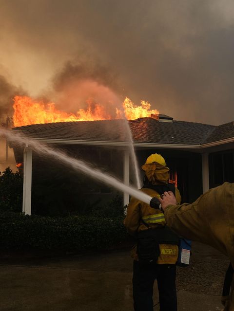Zwei Feuerwehrmänner versuchen ein brennendes Haus zu löschen