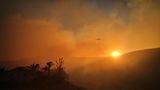 Was wie ein schöner Sonnenuntergang aussieht, ist der Rauch des Kenneth-Feuers im Stadtteil West Hills von Los Angeles, durch den Donnerstag ein Hubschrauber fliegt