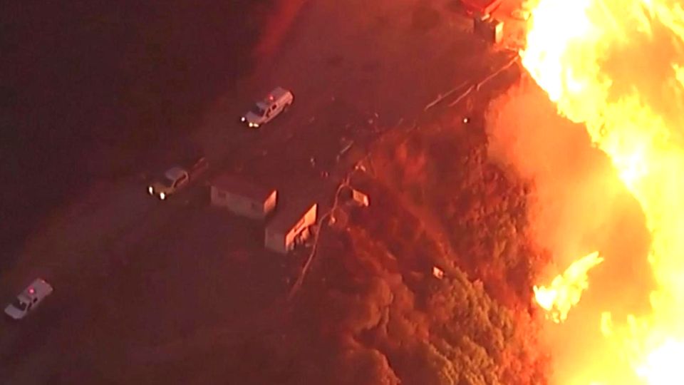 Feuerwehrleute fliehen vor riesiger Flammenwand