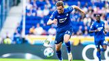 Sportfoto: Ein Fußballerspieler verfolgt den Ball, doch eine Taube kommt ihm in die Quere