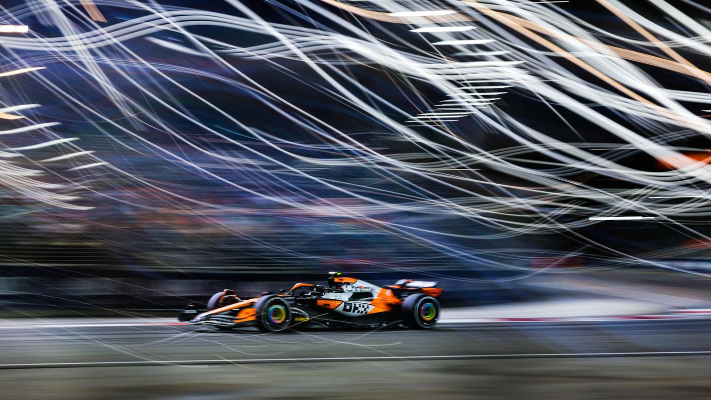 Sportfoto: Ein Formel1-Rennwagen fährt vor einem verschwommenen Hintergrund mit Lichtern