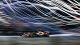 Sportfoto: Ein Formel1-Rennwagen fährt vor einem verschwommenen Hintergrund mit Lichtern
