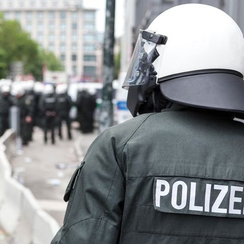 Thema Polizeigewalt Rückansicht eines Polizisten von der Bereitschaftspolizei mit weißem Helm