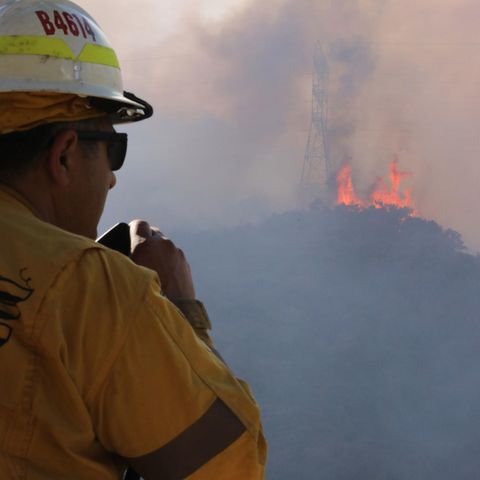 Ein Feuerwehrmann beobachtet lodernde Flammen auf einem Hügel in Los Angeles