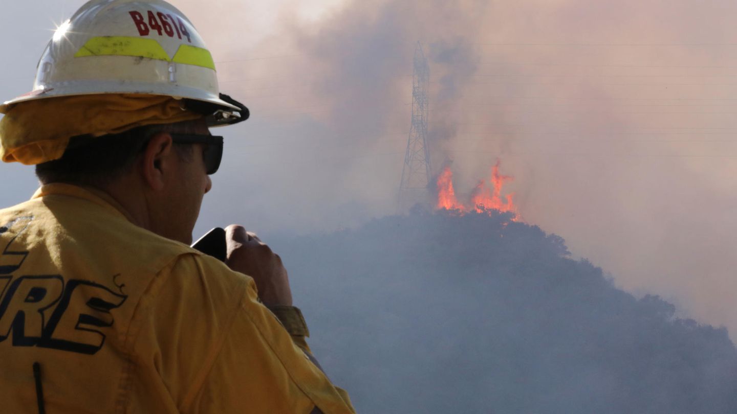 Ein Feuerwehrmann beobachtet lodernde Flammen auf einem Hügel in Los Angeles