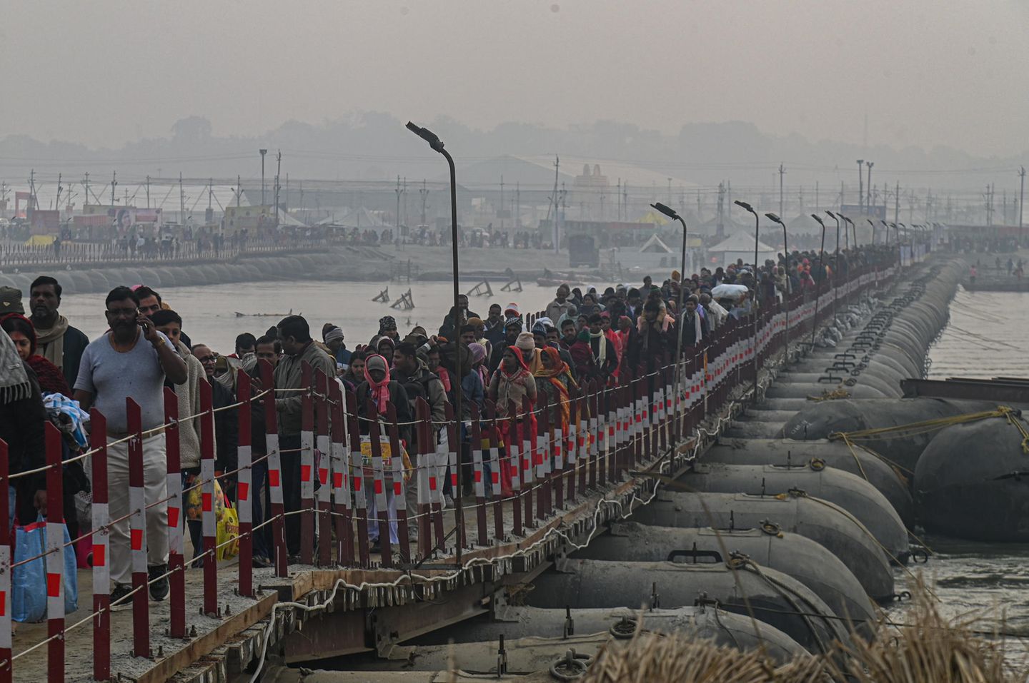 In Prayagraj ankommende Hindus überqueren eine schmale Brücke