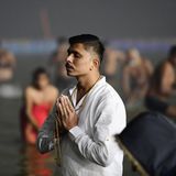 Ein junger Mann betet konzentriert und mit geschlossenen Augen am Fluss