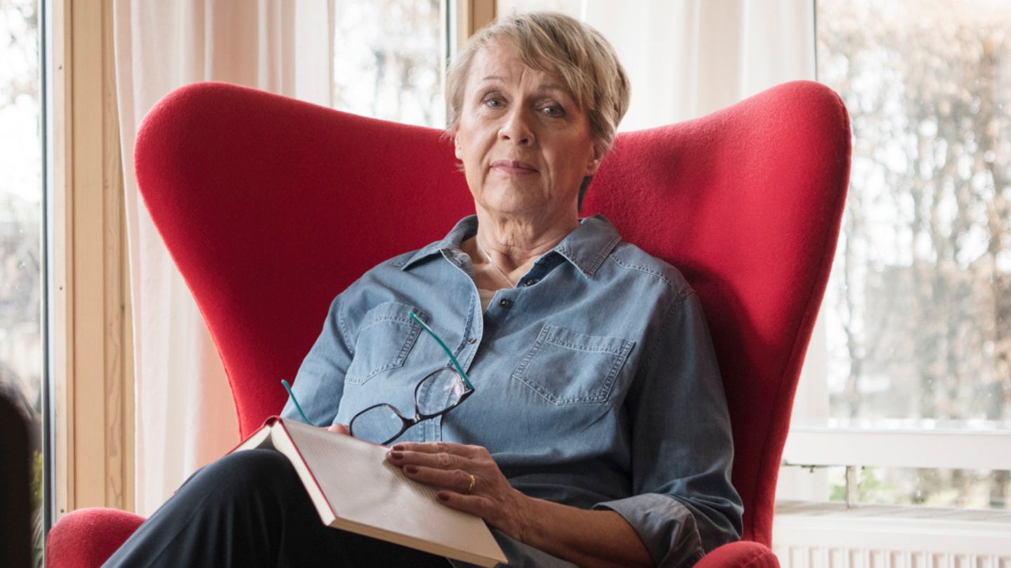 Inge Löhning sitzt in einem roten Sessel in ihrem Wohnzimmer