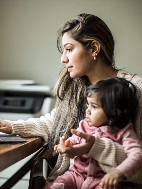 Eine Alleinerziehende sitzt mit ihrer Tochter auf dem Schoss am Laptop