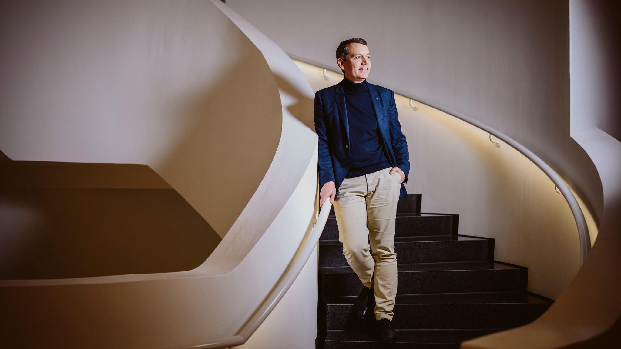 dm Chef Werner steht lächelnd auf einer Wendeltreppe