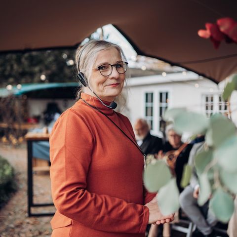 Traurednerin Kathrin Remé im kürbisfarbenen Oberteil mit Headset auf einer Hochzeit.