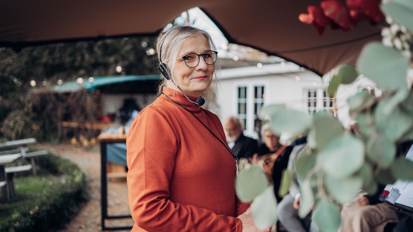 Traurednerin Traurednerin Kathrin Remé im kürbisfarbenen Oberteil mit Headset auf einer Hochzeit.