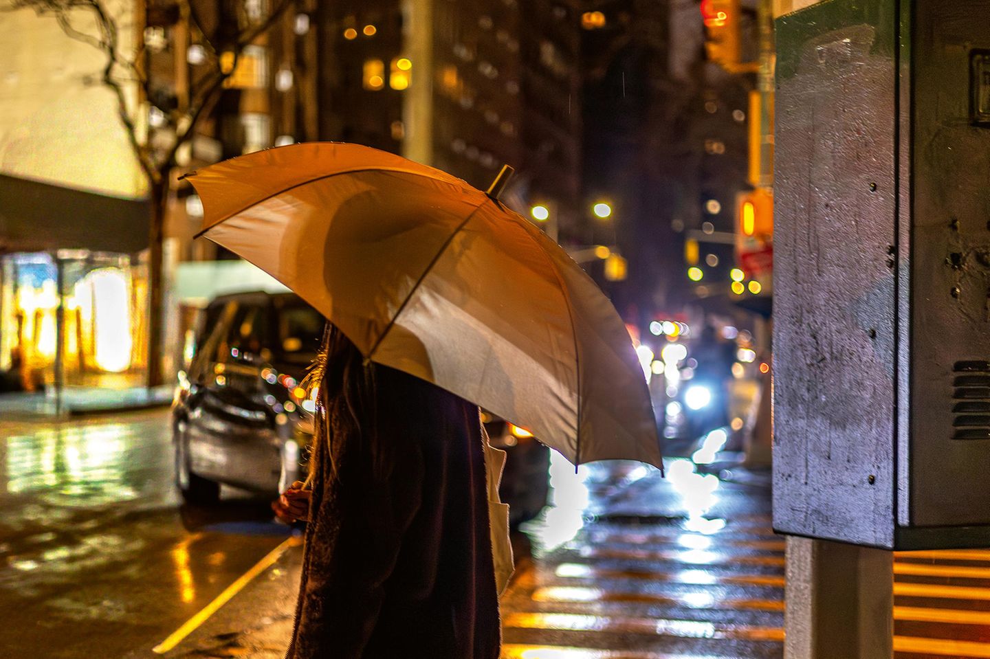 Eine Frau mit einem Regenschirm im dunkeln an einer Straße