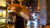 Eine Frau mit einem Regenschirm im dunkeln an einer Straße