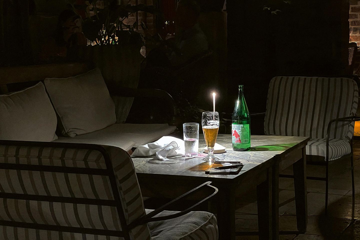 Ein Tisch mit Getränken wird einzig von einer Kerze erleuchtet
