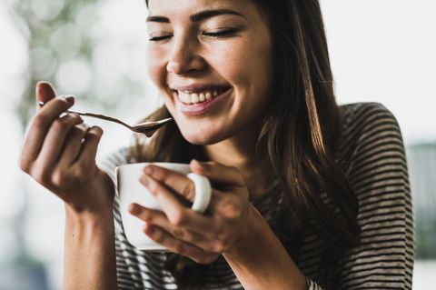 Frau trinkt Kaffee aus einem Kaffeevollautomat.