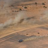 Der blaue Wagen hinterlässt eine staubige Bahn hinter sich, während der unermessliche Horizont vor ihm liegt