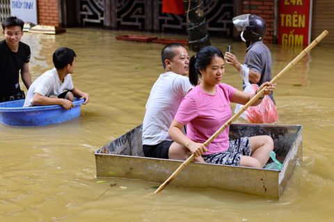 Naturkatastrophen Menschen retten sich mit Schüsseln vor den Wassermassen