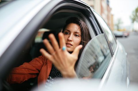 Bebilderung "Fluchen": Eine Frau sitzt im Auto und gestikuliert mit der Hand