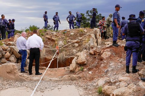 Südafrika: Polizeibeamte und privates Sicherheitspersonal stehen vor einem stillgelegten Goldminenschacht