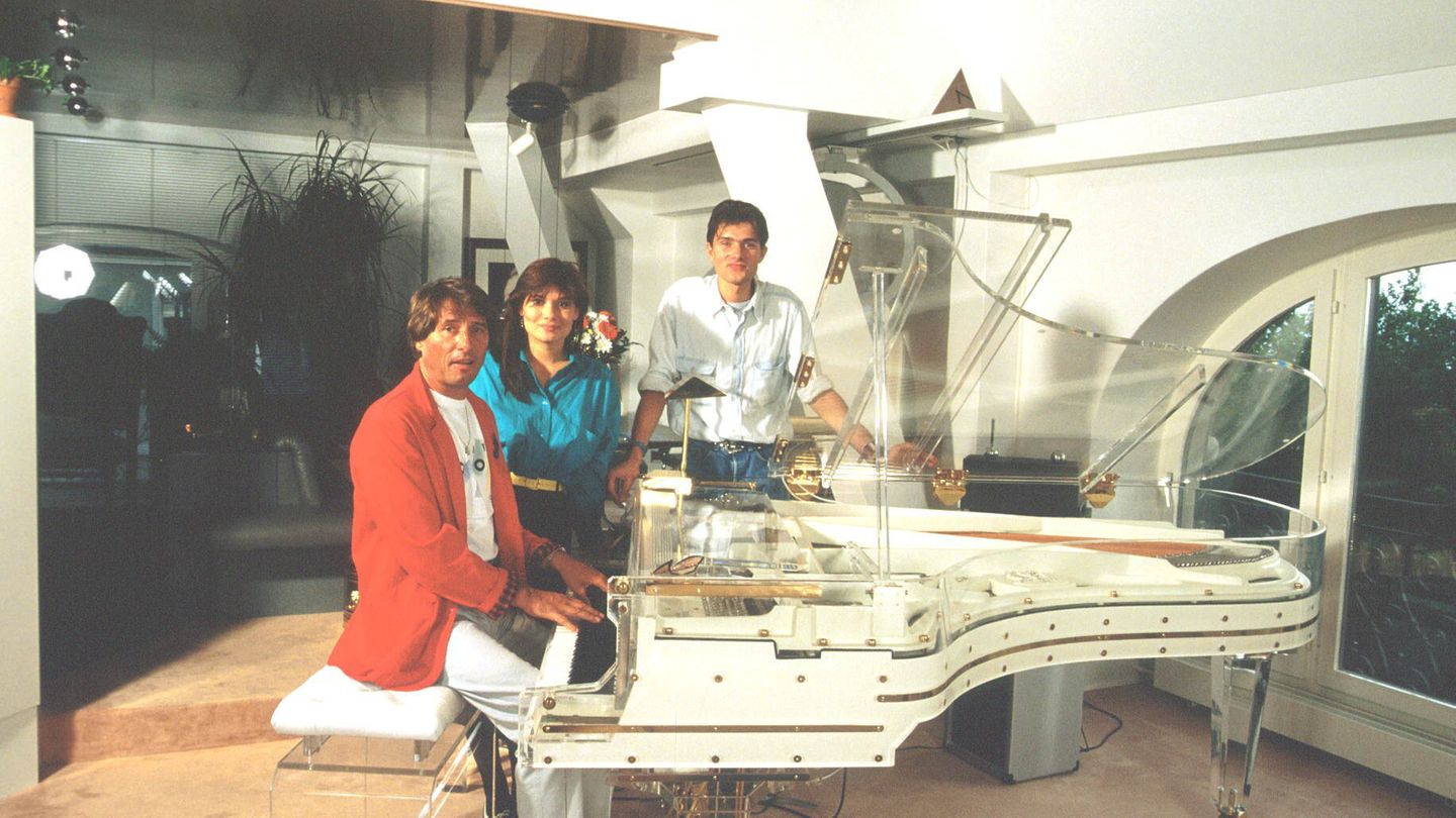 Udo Jürgens 1986 an seinem durchsichtigen Flügel mit Tochter Jenny und Sohn John